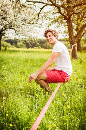 Man sitting on tightrope in field
