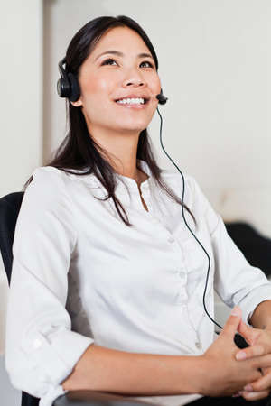 Businesswoman wearing headset at deskの写真素材