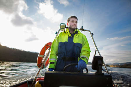 Worker driving boat in rural lakeの写真素材