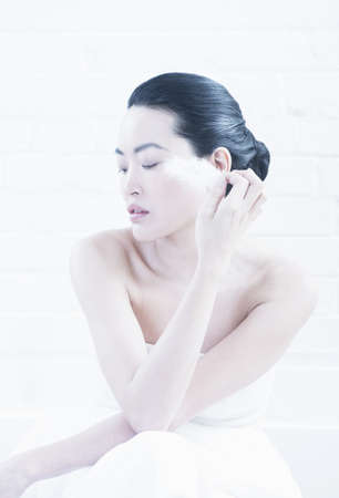 Nude woman wiping feather on cheekの写真素材