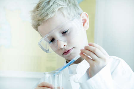 Boy wearing safety goggles doing science experimentの写真素材