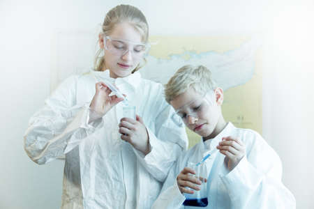 Brother and sister wearing safety goggles doing science experimentの写真素材