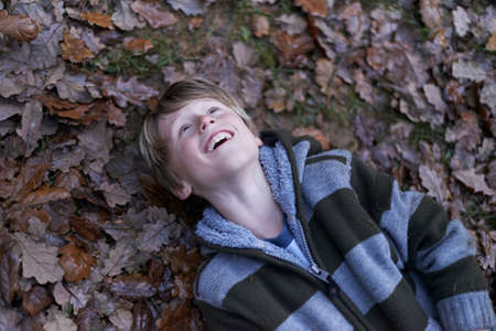 Boy lying on back on forest floorの写真素材