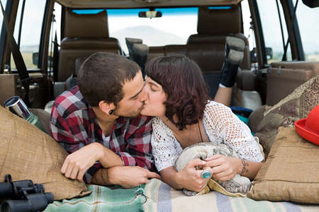 Young couple kissing in back of suvの写真素材