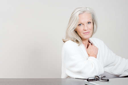 Middle aged woman in bathrobe sitting at table