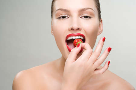 Young woman eating a strawberryの写真素材