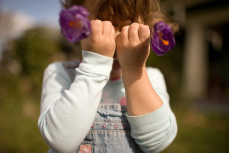 Young girl holding flowers in front of faceの写真素材