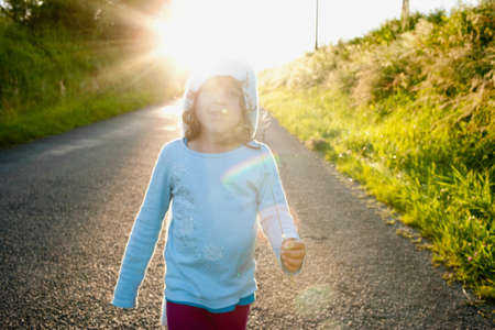 Girl walking down rural roadの写真素材