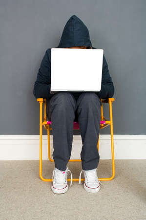 Young man wearing hooded top using laptopの写真素材