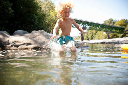 Boy jumping in riverの写真素材