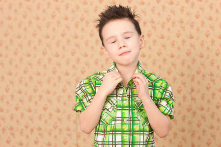 Boy buttoning collar with eyes closedの写真素材