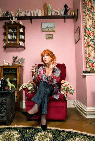Senior woman in living room with wine and cigarette, smiling