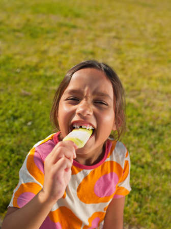 Girl biting into ice lolly, portraitの写真素材
