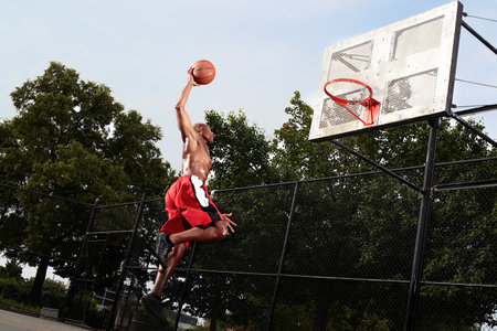 Young man leaping at basketball hoop