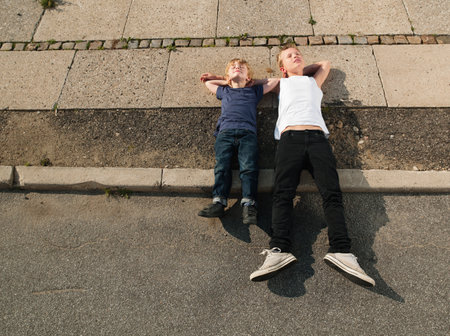 Brothers lying together on sidewalkの写真素材