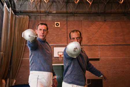 Senior and mature men holding fencing foils
