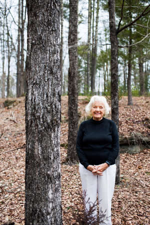 Portrait of senior woman in forest, hands claspedの写真素材