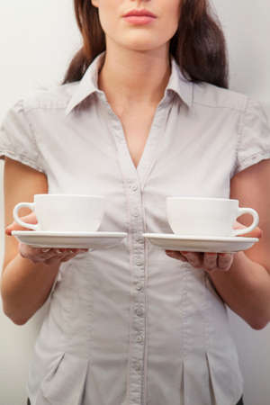 Young woman holding two teacupsの写真素材