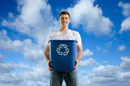 Man with recycling bin against blue skyの写真素材