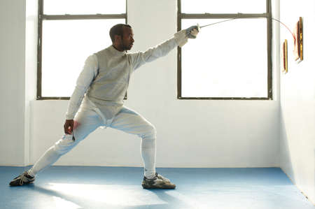 Male fencer holding foil to target, side viewの写真素材