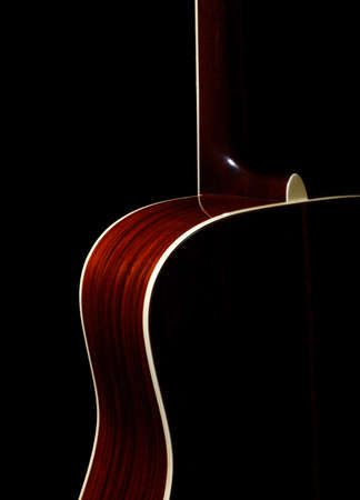 Acoustic guitar against black background