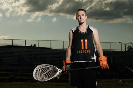Young sportsman holding lacrosse stick in sportsgroundの写真素材