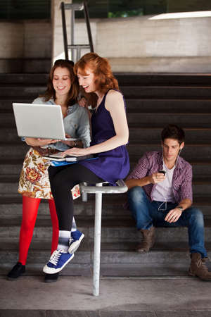 Two young woman looking at a laptop at the bottom of steps