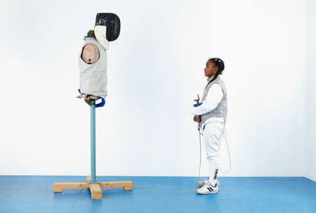 Girl in fencing gear looking at mannequin