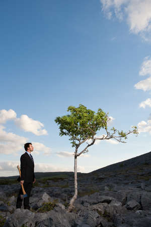 Businessman holding axe in remote landscapeの写真素材