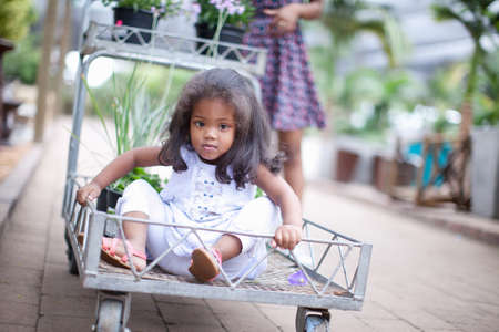 Girl sitting in cart at plant nurseryの写真素材