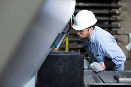 Worker using machinery in metal plant