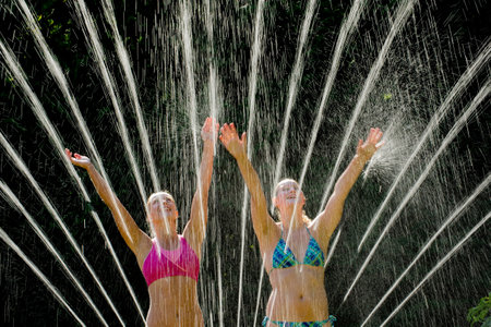 Teenage girls playing in sprinklerの写真素材