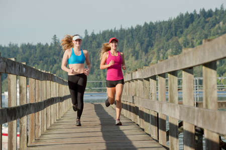 Teenage girls running on wooden dockの写真素材