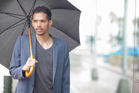 Young man holding umbrellaの写真素材