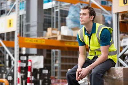 Man sitting on cardboard box in warehouseの写真素材