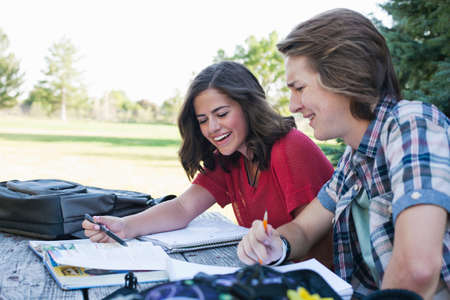 Teenage couple studying at picnic table in park