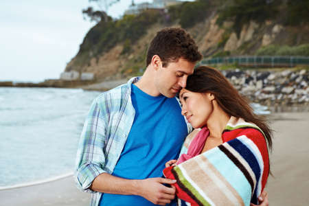 Young couple on beach, woman wrapped in towelの写真素材