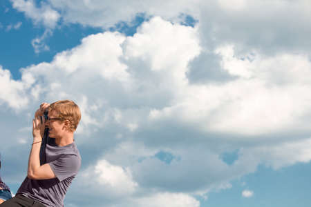 Young man taking photograph with clouds in sky