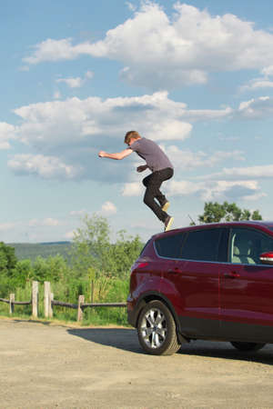 Young man jumping off carの写真素材