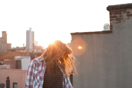 Young woman shaking hair on city rooftopの写真素材