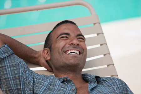 Man relaxing in lawn chair by pool