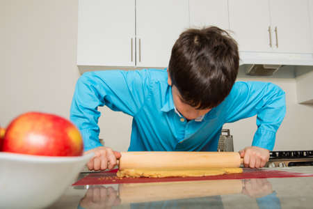 Boy rolling dough in kitchenの写真素材