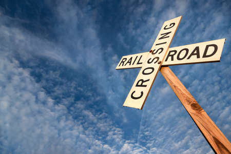 'Railroad crossing' sign under blue skyの写真素材