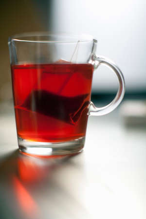 Tea bag steeping in glass mugの写真素材