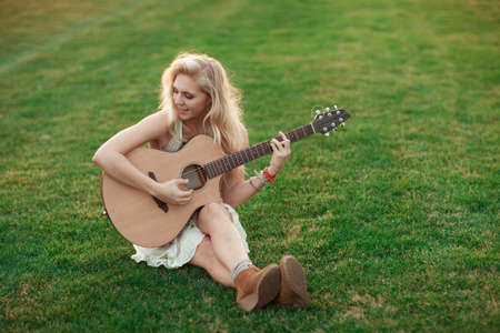 Woman playing guitar in grassの写真素材