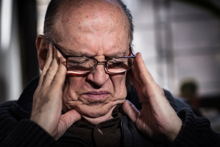 Senior man with eyes closed, wearing glasses, looking stressedの写真素材