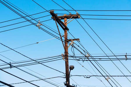 Cables attached to telegraph pole against blue sky