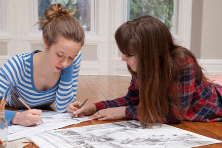 Girls lying on floor drawing picturesの写真素材