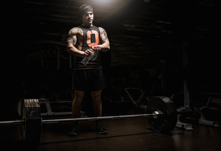 Young man holding water bottle in gymの写真素材