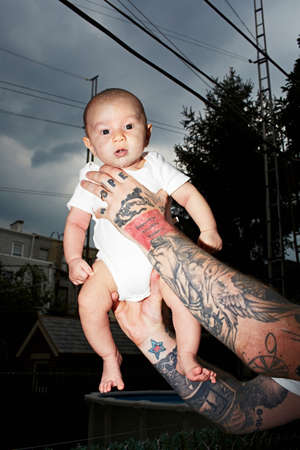 Father with tattooed arms holding baby sonの写真素材